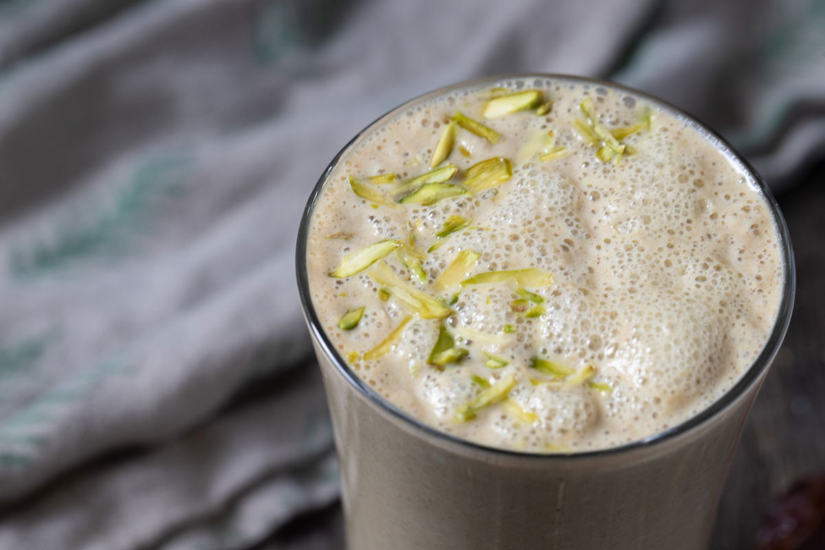 Top of a glass of date milk, garnished with pistachio slivers
