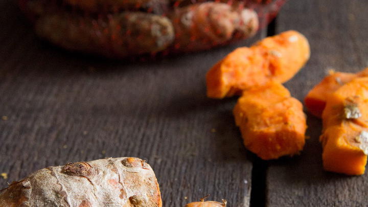 Fresh turmeric laid out in front of a bag. Some of it is freshly peeled.