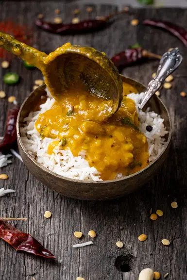 Pouring Gujarati dal over rice.
