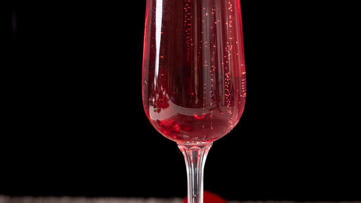 Rose mimosa garnished with a strawberry and decorated with rose petals.