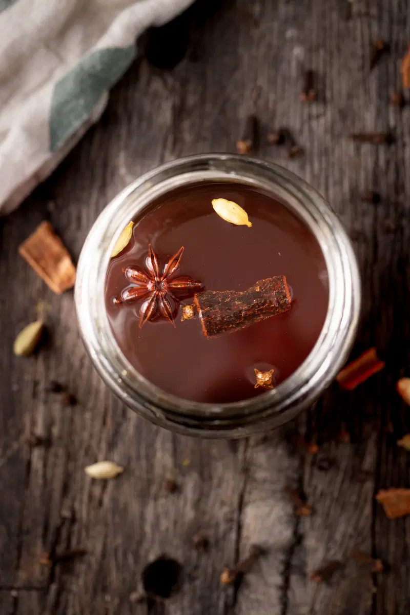 Chai liqueur in a jar with cinnamon, cardamom, and star anise.