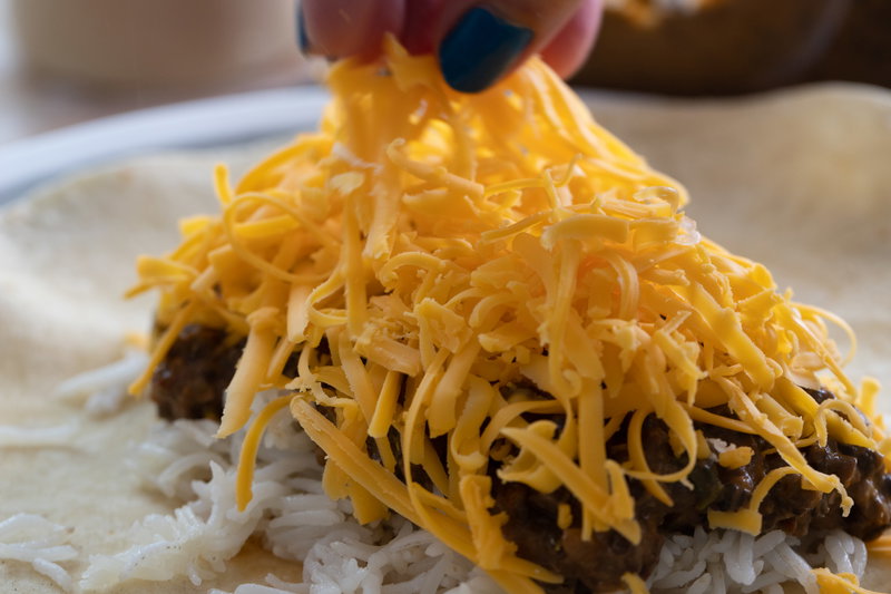 Adding cheddar cheese to the dal makhani burrito