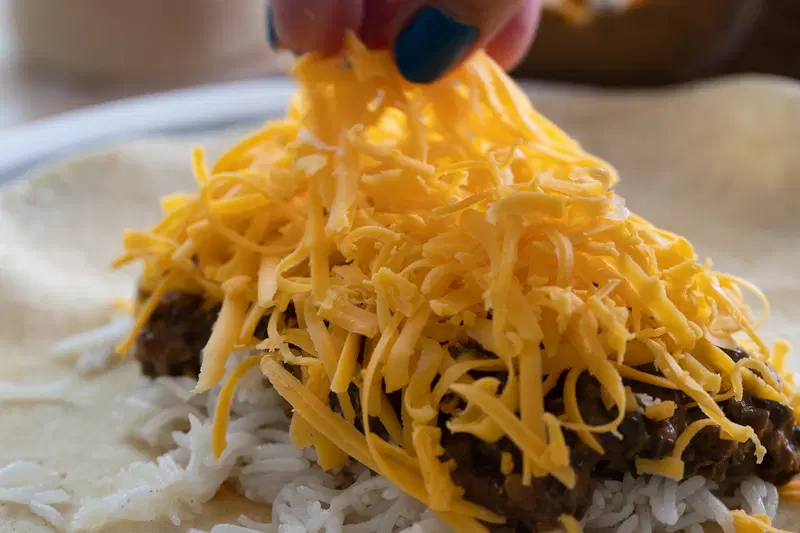 Adding cheddar cheese to the dal makhani burrito