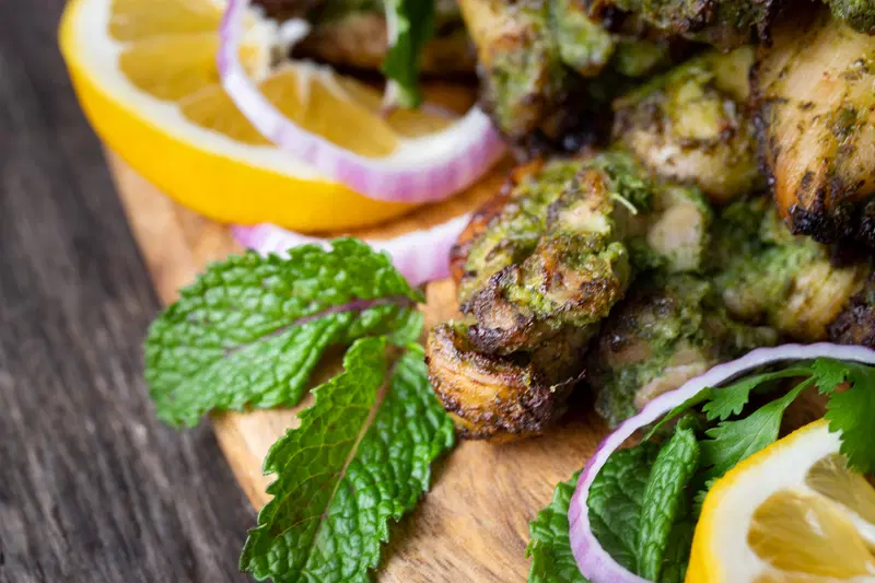 Hariyali chicken served with mint leaves, lemon slices, and raw onion.
