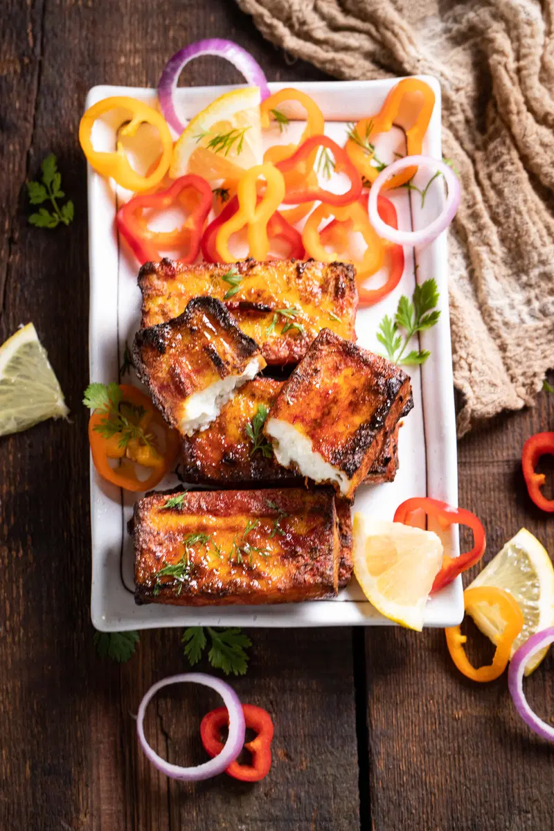 Plate of paneer tikka served with onions and peppers