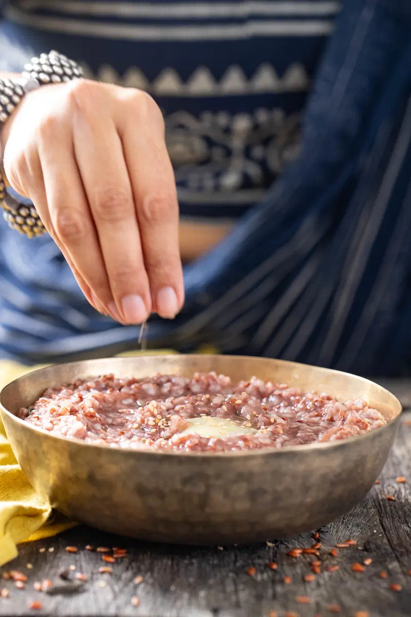 Finishing yavagu with some sesame seeds, an optional topping.