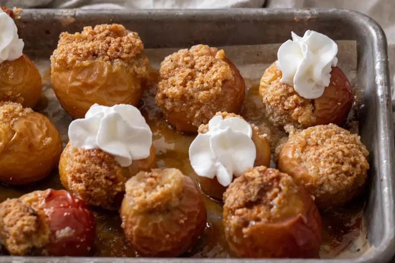 Full baking sheet of mini apples with whipped cream.