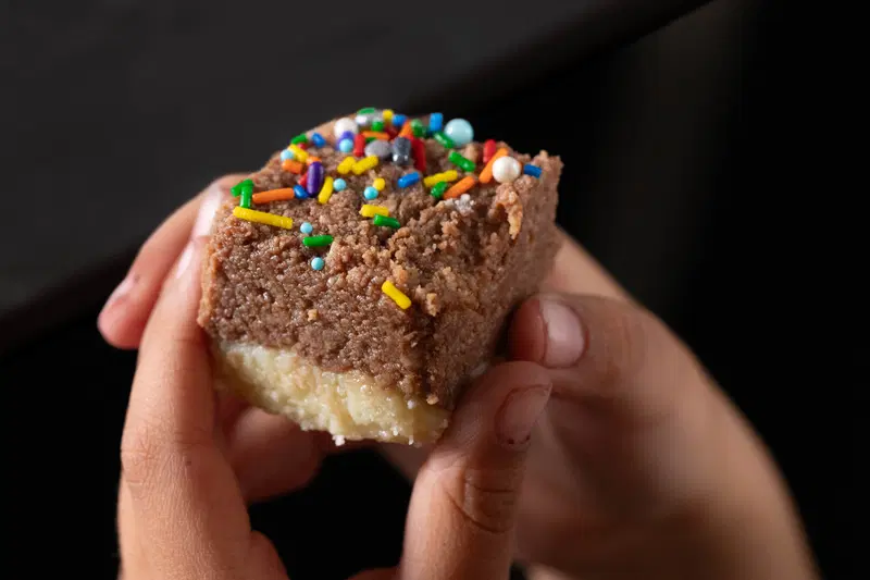 Small hands holding chocolate barfi piece