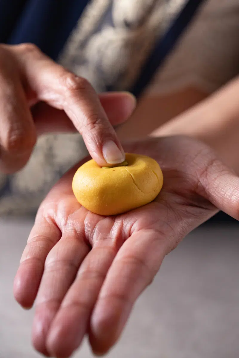 Pressing a pistachio into the kesar peda.