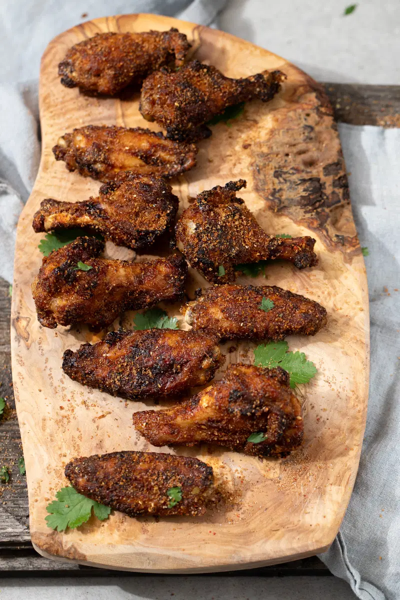 Spicy dry rubbed chicken wings on a wooden platter